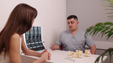 Hasta bakımı, omurga teşhisi, tıbbi uzmanlık. Profesyonel klinikte, tıbbi pratisyen hasta ile omurga röntgeni görüşlerini paylaşıyor, omurga modeli ile anatomiyi vurguluyor..