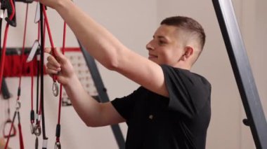 Gülümseyen terapist, uzaklaştırma terapisi, terapi ipleri. Gülümseyen terapist askıya alma terapisi iplerini ve klipslerini düzeltiyor, rehabilitasyon veya klinikte fizyoterapi seansı için ekipman hazırlıyor.