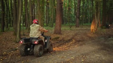 Miğferli grup, seyir halindeki orman, ATV yolu. Kask ve kamuflaj takan grup üyeleri, far açıkken ATV 'lerde orman yolunda ilerliyorlar..