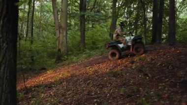 ATV grubu, orman yolu, dinamik yolculuk. Toprak yolda ATV sürerken, grup ormanın yoğun yeşilliğini, heyecan ve sükunetin tadını çıkarıyor..