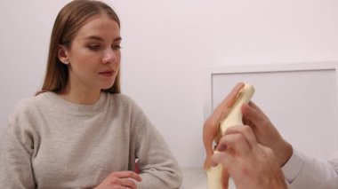 Kadın hasta, hasta bakımı, tıbbi danışmanlık. Muayene sırasında, kadın hasta yakından ilgilenir. Tıp uzmanları diz anatomisini modelle tanımlar..
