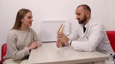 Hasta eğitimi, diz anatomisi, tıbbi model. Tıbbi uzman, kadını klinik ortamda dizlerinin anatomisi hakkında eğitti..