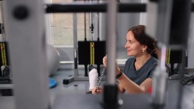 Fiziksel rehabilitasyon, çocuk kondisyonu, hareketlilik gerilimi. Kadın rehabilitasyon uzmanı, çocuğu fiziksel eğitim araçlarıyla bacak esnetme yoluyla destekliyor.