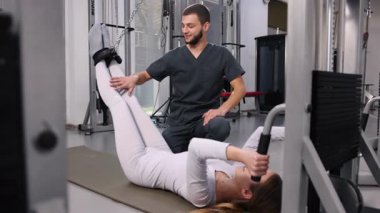 Kadın esneme hareketleri, rehabilitasyon paspası, destekli esneme hareketleri. Erkek terapist, kadınların bacaklarını açmasına yardım ediyor..