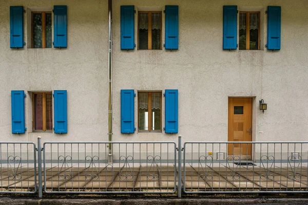 青いシャッターと茶色のフロントドアを持つ5つの窓のある建物の外観 — ストック写真