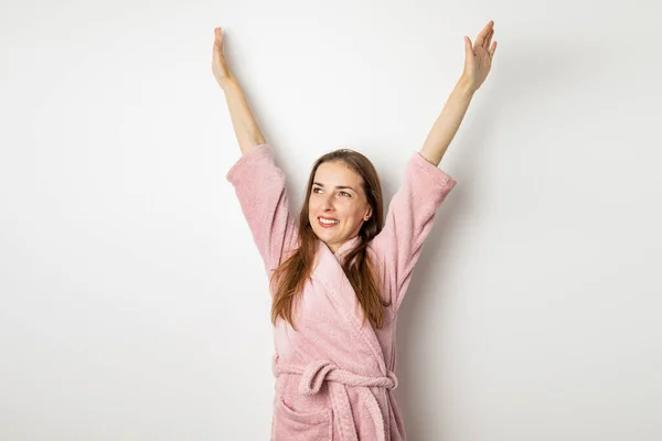 白い背景に立ち上がった手でバスローブを着た若い女性の笑顔 — ストック写真