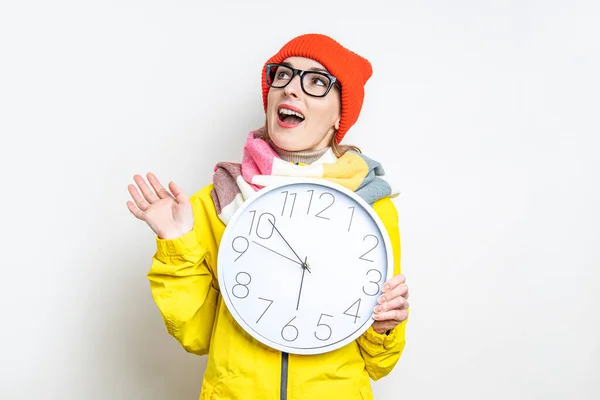 Mujer Joven Mira Sorprendida Mientras Sostiene Reloj Sobre Fondo Claro — Foto de Stock
