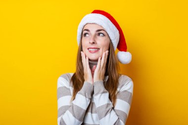 Sarı arka planda ellerini çenesine koyan düşünceli genç bir kadın..