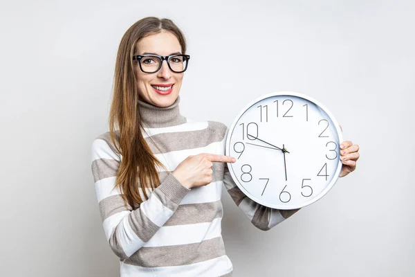 Mujer Joven Sonriente Señalando Reloj Pared Sobre Fondo Claro — Foto de Stock