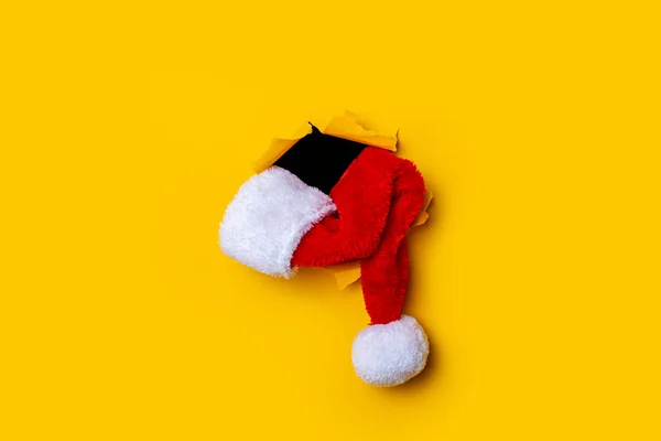 Kapelusz Santa Claus Leży Dziurze Rozdartym Żółtym Tle — Zdjęcie stockowe