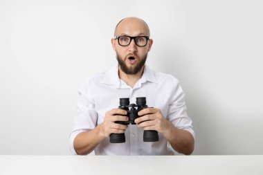 Beyaz arka planda dürbünlü genç adam şaşırdı..