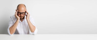 Gözleri kapalı genç bir adam beyaz bir arka planda masada otururken ağırlıklara tutunuyor. Pankart.