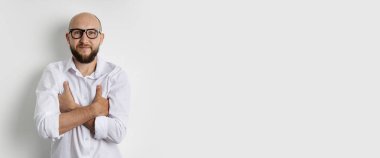 Kolları çapraz olan gülümseyen genç adam beyaz arka planda duruyor. Pankart.