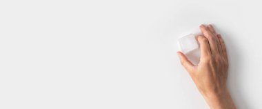 Beyaz arka planda buz küpünü tutan bir kadının eli. Üst manzara, düz yatış. Pankart.