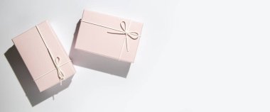 Beyaz arka planda iki soluk pembe hediye kutusu. Üst manzara, düz yatış. Pankart.