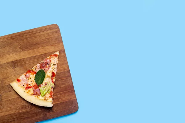 Kawałek Gorącej Świeżej Pizzy Leży Drewnianej Desce Niebieskim Tle Widok — Zdjęcie stockowe