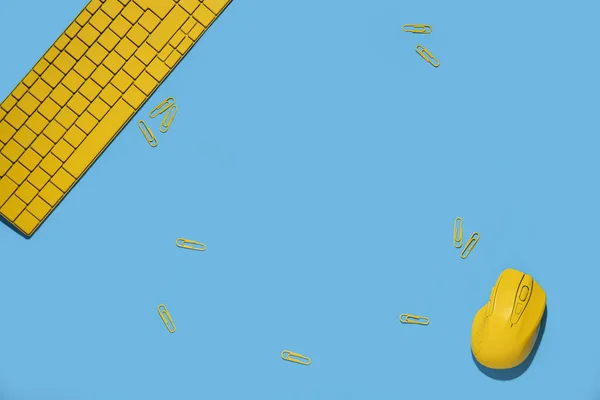 黄色のキーボード ワイヤレスコンピュータのマウス 青い背景の紙クリップ トップビュー フラットレイアウト — ストック写真