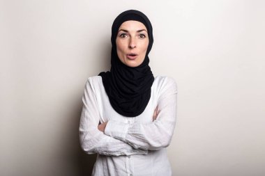 Beyaz gömlekli, şaşkın yüzlü ve tesettürlü genç bir kadın..