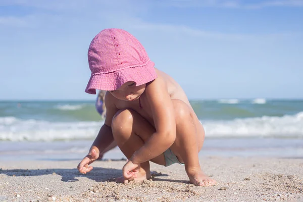 Child blond girl plays, builds castles on the beach