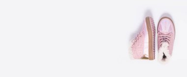 Beyaz arka planda pembe çocuk ayakkabıları. Üst manzara, düz yatış. Pankart