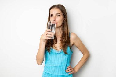 Genç kadın içme suyu cam beyaz bir arka plan üzerinde.