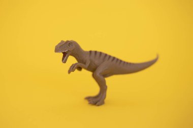 Sarı arka planda plastik dinozor oyuncağı.