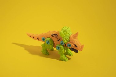 Sarı arka planda plastik dinozor oyuncağı.