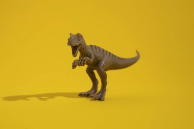 Sarı arka planda plastik dinozor oyuncağı.