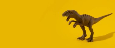 Sarı arka planda plastik dinozor oyuncağı. Pankart.
