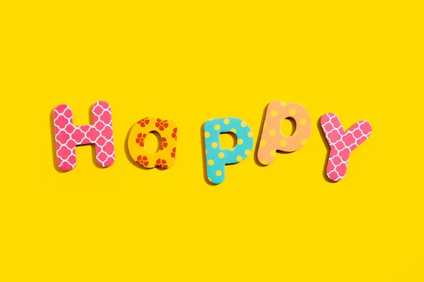 Słowo Szczęśliwy Wielobarwnych Liter Alfabetu Żółtym Tle Widok Góry Płaski — Zdjęcie stockowe
