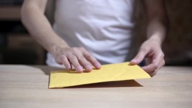 Adam bildirim mektubunu açar. Sadece eller görünür.