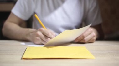 Bir adamın sinematik yakın çekimi göndermeden önce zarfa bir mektup koymaktır. Yazışma, hat, iletişim kavramı