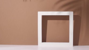 Kahverengi bir duvarın arka planında palmiye dalının gölgesi olan soyut bir figür.