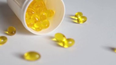 Kapsüller beyaz arka planda ambalajlı D vitamini döküntüleri.