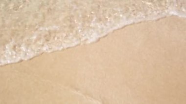 Deniz dalgaları kumlu sahili yıkıyor.