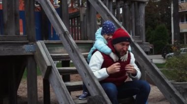 Babam sonbahar parkında bir çocukla oynuyor.