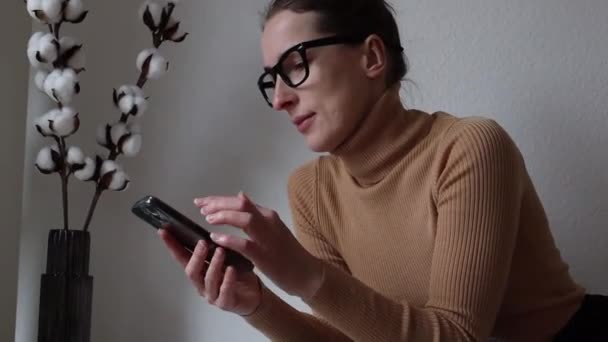 Gözlüklü Genç Kadın Odadaki Telefona Bakıyor — Stok video