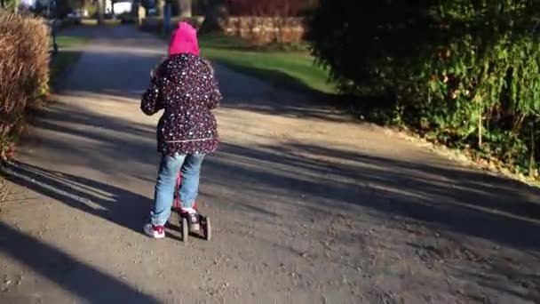 子供の女の子は公園のスクーターに乗る — ストック動画