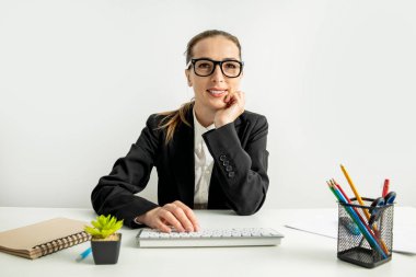Klavyeli gülümseyen genç kadın iş yerinde masada oturuyor..