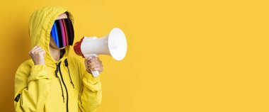 Sarı arka planda sarı ceketli, megafonlu siber punk gözlüklü genç kadın. Pankart