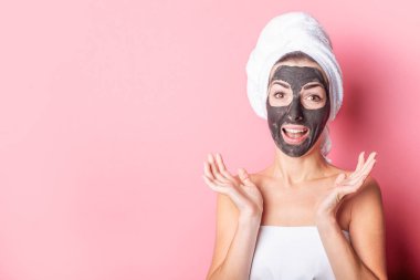 Kozmetik yüz maskesi, spa prosedürleri. Pembe arka planda yüzü maskeli bir kız.