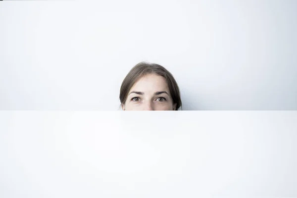 Молодая Женщина Выглядывает Белого Картона Белой Стене — стоковое фото