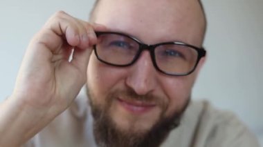 Gülümseyen genç adam gözlük takar ve der ki:.
