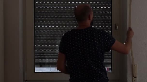 Unge Man Öppnar Fönsterluckan Och Tittar Genom Fönstret — Stockvideo