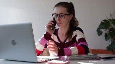Telefonda konuşan ve evde çalışan bir kadın.
