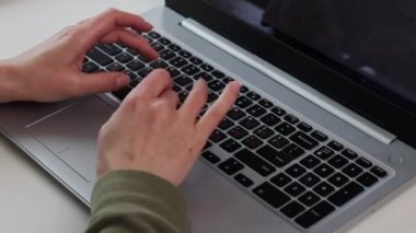 Beyaz bir masada dizüstü bilgisayarda yazı yazan bir kadın..