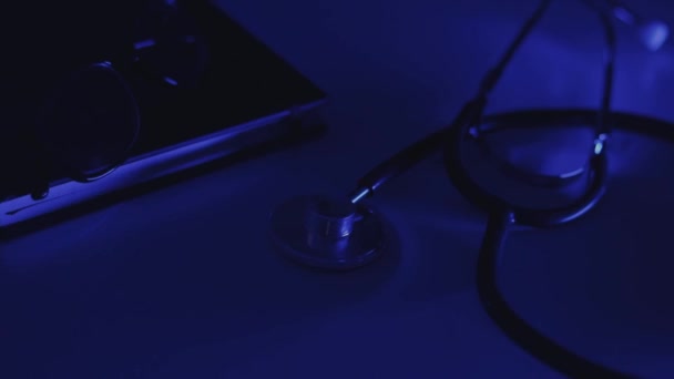 Stetoskop Pamiętnik Okulary Leżą Stole Niebieskim Migającym Światłem — Wideo stockowe