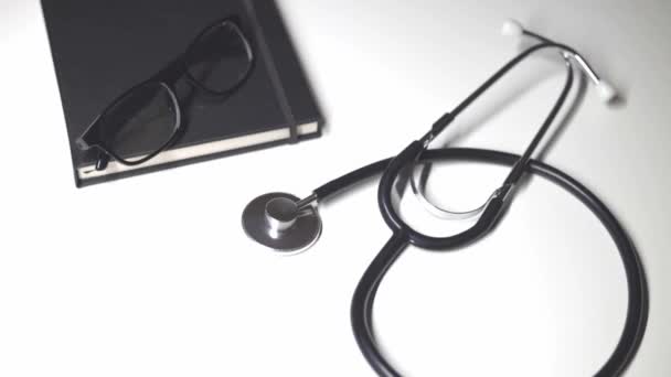 Stethoskop Tagebuch Brille Liegen Auf Weißem Hintergrund Draufsicht Flache Lage — Stockvideo