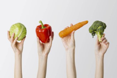 Beyaz arka planda lahana, paprika, havuç ve brokoli tutan kadın eli kolajı..