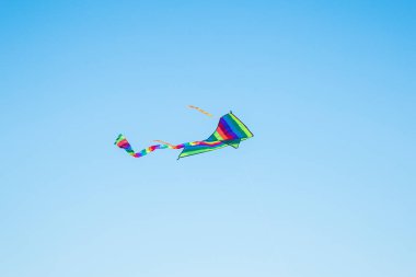 Mavi gökyüzünde uçan renkli uçurtma. Yaz oyunları ve eğlence.